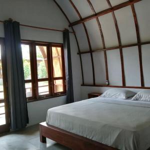 武吉拉旺Gino's Place - Bungalows and Restaurant的一间卧室设有一张大床和两个窗户。