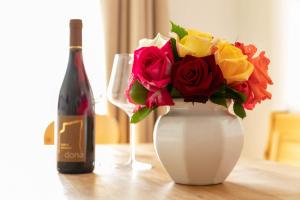 拉纳Landhaus am Gries的白色的花瓶,上面有一束玫瑰花和一瓶葡萄酒