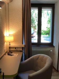 欧丹库尔Les Tilleuls Montbeliard Sud Audincourt的客房设有书桌、椅子和窗户。