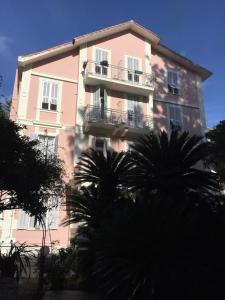 博尔迪盖拉Hotel Lucciola的前面有棕榈树的粉红色建筑