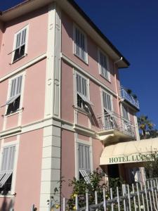 博尔迪盖拉Hotel Lucciola的粉红色的酒店,前面设有围栏