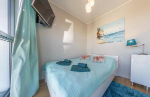 米兹多洛杰Horyzont by Baltic Home的一间卧室配有一张带蓝色床单的床和一台电视。