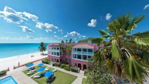 基督教堂市南方棕榈海滩俱乐部酒店的海滩上的粉红色建筑,配有椅子和海洋