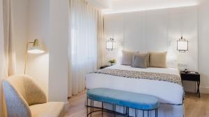 马拉加莫里纳拉里欧酒店的卧室配有一张白色大床和一把椅子