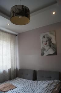 罗兹Red Apartament的卧室配有一张床和一张女人的照片