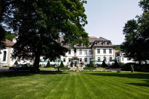 萨勒河畔巴特诺伊施塔特拜德纽斯塔德特城堡酒店的一座大型白色房子,设有大草地庭院