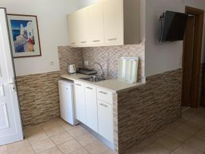 卡西奥皮Kassiopi Bay的厨房配有白色橱柜和水槽