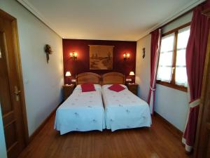 埃特克萨拉尔Aldalurberea的一间卧室配有一张带两个红色枕头的床