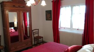 La Neuville-du-BoscGite de la Haute Verdière的一间带镜子的卧室和一个带红色窗帘的梳妆台