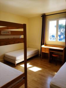 圣皮耶尔基贝龙Home des Pins SARL的一间卧室配有双层床、一张桌子和一个窗户。