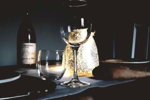 方丹·德·沃克吕兹Vue panoramique sur le château,montagne et grottes的两杯酒杯坐在桌子上,并配上一瓶葡萄酒
