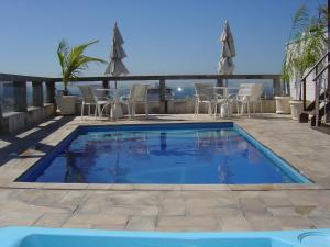 里约热内卢奥古斯托科帕卡巴纳酒店的一个带椅子和遮阳伞的庭院内的游泳池