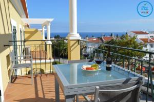 珀彻斯Encantador T1 praia Senhora da Rocha - Algarve的阳台上的桌子上放着一杯葡萄酒和一碗水果