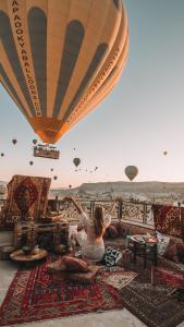 格雷梅Osmanli Cappadocia Hotel的坐在地毯上看热气球的女人