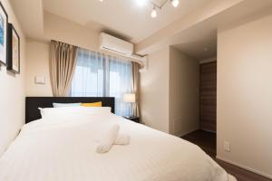 东京HIZ HOTEL Ginza的卧室配有白色的床和2拖鞋