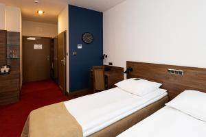 威赫罗伏Hotel Olimp Business & Spa的一间卧室设有两张床,墙上挂着一个时钟。