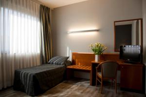 罗马祖恩酒店的酒店客房配有一张床和一张书桌及一台电视