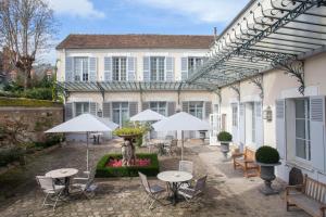 枫丹白露德隆德里斯酒店的房屋前设有带桌子和遮阳伞的庭院。
