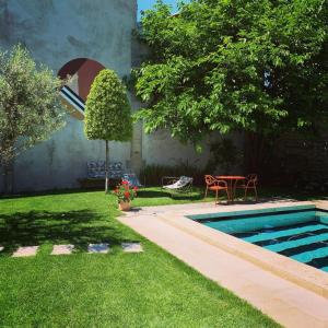 圣雷米普罗旺斯Le petit hotel的后院设有游泳池、桌子和草坪