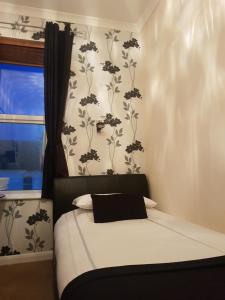 海斯廷斯森拉克旅馆的卧室配有一张铺有白色床单的床,墙上挂着鲜花。