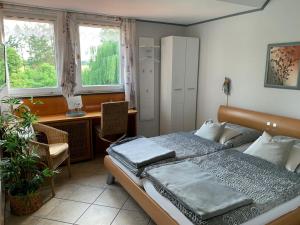代斯特尔山麓巴德明德尔Gästehaus Villa Kreativ Susanne Lay的一间卧室配有一张床、一张书桌和两个窗户。