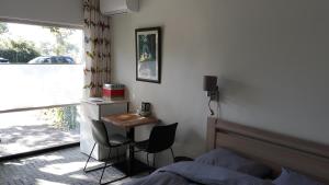 WerkendamBiesbosch Bed & Breakfast Werkendam的一间卧室配有一张床、一张书桌和一个窗户。