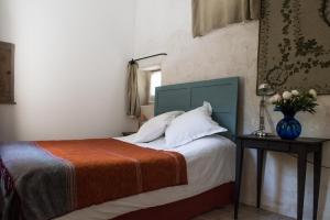 圣萨蒂南艾普特乐多迈纳圣让酒店的一间卧室,配有一张床,桌子上放着花瓶