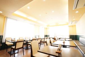 鹿屋市ホテル大藏的餐厅设有桌椅和大窗户。