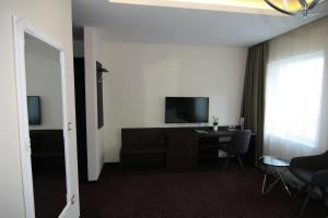 瓦茨Vácz Hotel的酒店客房配有电视、桌子和椅子。