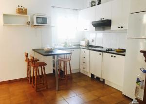 格拉纳迪利亚德亚沃纳WIFI TENERIFE SUR GUEST HOUSE的厨房配有白色橱柜和带凳子的桌子