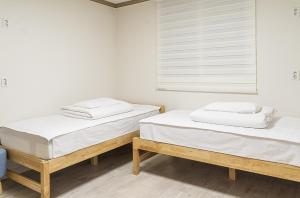 庆州花郎旅馆的配有2张床的白色墙壁和窗户。