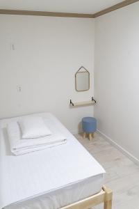 庆州花郎旅馆的白色客房,配有床和蓝椅
