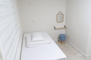 庆州花郎旅馆的白色的客房配有床和镜子
