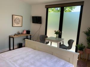 赞德沃特Charming private guesthouse Air by the Beach的一间卧室配有一张床、一张桌子和一个窗户。
