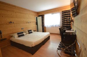 布里昂松艾德维斯酒店的一间卧室,卧室内配有一张床和一把椅子