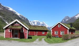 BriksdalsbreTrollbu Aabrekk gard的山前屋顶上两个红色谷仓,上面有草