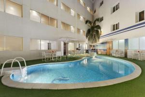 马斯喀特库隆海滩华美达酒店的一座建筑物中央的游泳池