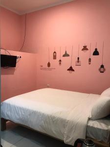 三宝垄RoomZ Budget Residence的卧室配有粉红色墙壁上的白色床