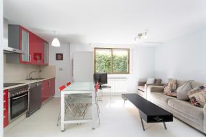 米尼奥Housingcoruña Apartamento Playa Miño 02的厨房以及带红色橱柜和沙发的客厅。