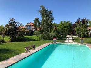 TiszaszentimrePatrimonium Wellness Apartments的房屋旁带长凳的游泳池