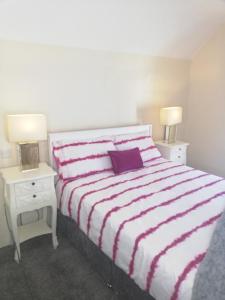 阿达拉The Barn @Ardhill House的一间卧室配有一张带紫色枕头和2个床头柜的床