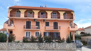 扎达尔玛丽亚膳食公寓的粉红色的房子设有阳台和石墙