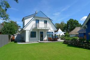 奥茨塞巴德·迪尔哈根TIDENHUS的蓝色屋顶和庭院的白色房子