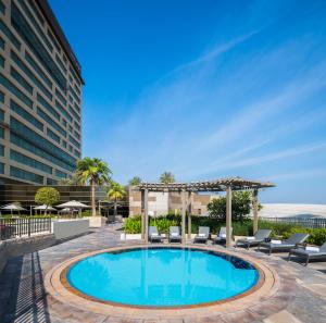 迪拜古赖尔瑞士生活酒店的一个带椅子和凉亭的酒店游泳池