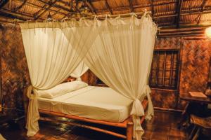 泰泰Flower Island Resort的一间卧室配有带窗帘的天蓬床