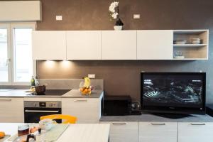 格拉多Cattleya的厨房配有白色橱柜和平面电视。