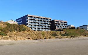 林肯市Starfish Manor Oceanfront Hotel的海滩旁山顶上的建筑