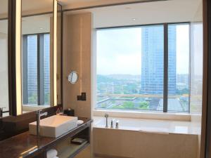 福州福州仓山凯悦酒店的带浴缸和盥洗盆的浴室以及大窗户。