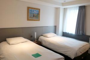 首尔明洞托马斯酒店的配有窗户的酒店客房内的两张床