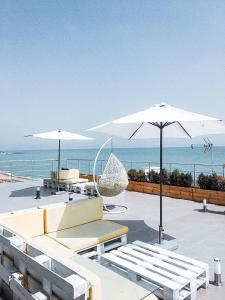 切尔诺莫斯克Klaster SeaView Hotel的一个带两把白色遮阳伞和椅子的庭院和大海